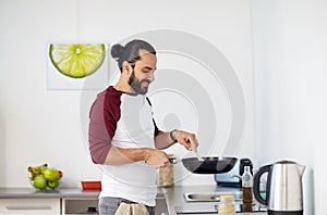 Man with frying pan cooking food at home kitchen photo