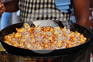 Man frying spicy snack or entree dish similar to a fritter, bhajji on street photo