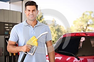 Man with fuel pump nozzle at self service gas station