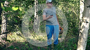 Man with full basket of mushrooms looking for his GPS signal on smartphone