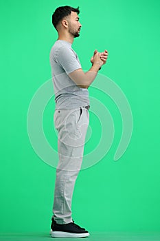 A man, full-length, on a green background, pleads