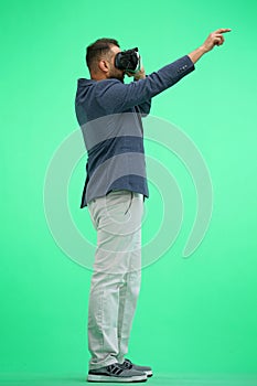 Man, full-length, on a green background, wearing VR glasses