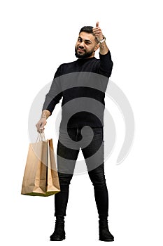 A man, full-length, on a white background, with bags, shows a thumbs up