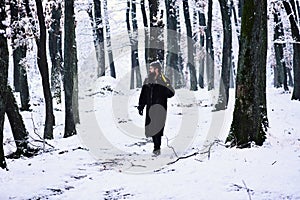 Man in fur coat in forest with axe on shoulder