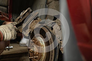 A man in a garage removes a brake pad from a disc. A man is replacing an old brake pad with a new one in his garage. A