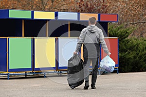 Man with garbage at recycling point outdoors, back view