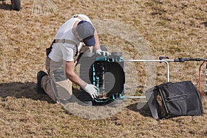 Man gardener cleaning machine scarifier from old dry grass on the lawn