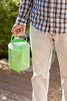 Man gardener holding watering can in garden