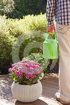 Man gardener holding watering can in garden