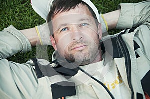 Man gardener resting lying on grass, portrait