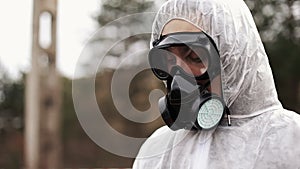 Man in gas-mask and bio-hazard suit looks down taking notes on his tablet