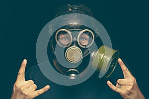Man in gas mask with crazy eyes making rock sign by both hands
