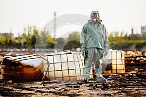 Man with gas mask and green military clothes explores barrels af
