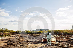 Man with gas mask and green military clothes explores barrels af