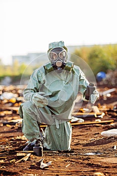 Man with gas mask and green military clothes explores barrels af