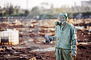 Man with gas mask and green military clothes explores barrels af