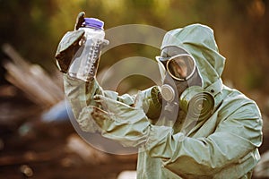 Man with gas mask and green military clothes explores barrels af