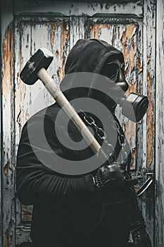 Man with gas mask and a hammer in machine room. Nuclear, Biological and Chemical danger concept