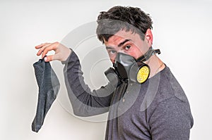 Man with gas mask is holding dirty stinky sock