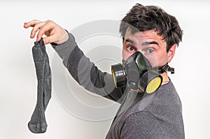 Man with gas mask is holding stinky sock