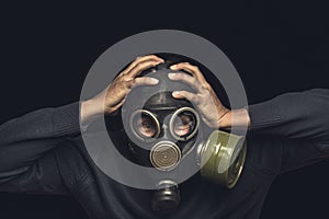 Man in gas mask holds his hands behind his head, emotion of panic and catastrophe or disaster concept