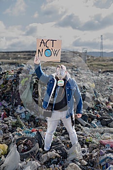 Man with gas mask and placard poster on landfill, environmental concept.