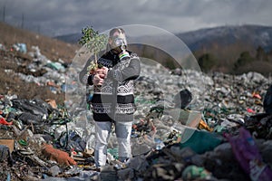 Man with gas mask and plant on landfill, environmental concept.