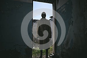 a man in a gas mask is standing in an old building in the doorway
