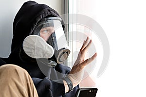 A man in a gas mask touches the glass with his hand and looks out the window