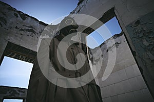 A man in gas mask walking inside an old building