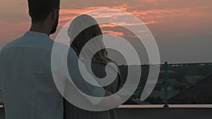 man gently hugs girl and carefully covers blanket on summer evening at sunset