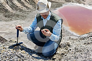 Man geologist examines a rock sample in a desert area