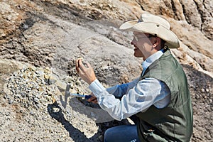 Man geologist examines a rock sample in a desert area