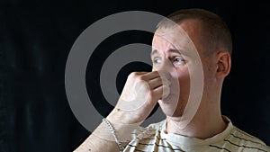 Man gestures a bad smell with his hand, closes his nose with his hands and acts nausea, on a black background