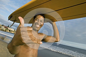 Man Gesturing While Carrying Surfboard On Head