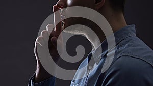 Man gesturing silence isolated on black, conspiracy theories, top secret concept