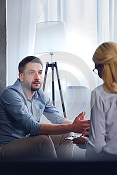 man gesturing and talking to female counselor while she writing in clipboard