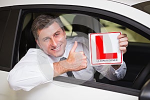 Man gesturing thumbs up holding a learner driver sign