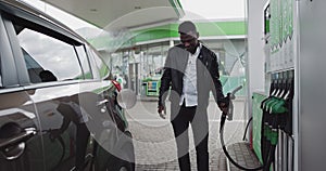 A Man Gets Out Of The Car At The Gas Station. Filling Benzine Gasoline Fuel In Car At Gas Station. African American Man