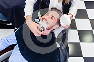 Man getting beard shave in barber salon