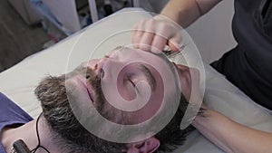 Man getting a face massage. beauty procedure, prevention of skin aging. lying in the office of the kasmetologist