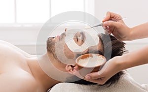 Man getting facial nourishing mask at spa salon