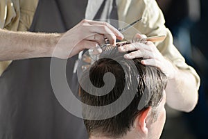 man getting haircut at barber shop. Hairdresser cutting hair of customer at salon.