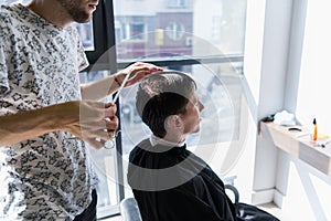 Man getting haircut at barber shop. Hairdresser styling hair of customer at salon.