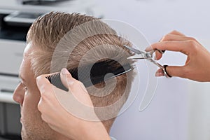 Man Getting Haircut From Hairdresser At Salon