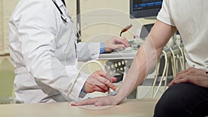 Man getting his wrist bones checked by doctor using ultrasound scanner
