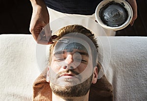 Man getting a mud mask at a spa