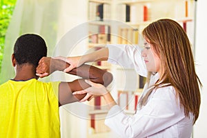 Man getting physical arm treatment from physio therapist, her hands working on his shoulder and elbow, medical concept