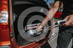 Man getting ready for holiday, vacation, putting a luggage into the car trunk, leisure time, tourism concept