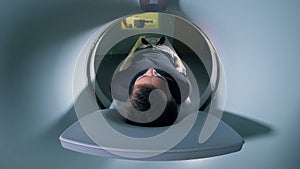 A man is getting scanned by a magnetic resonance imaging mechanism